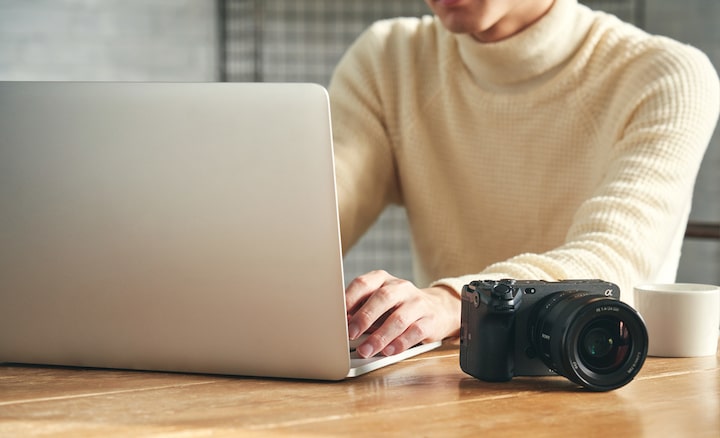 Image of A person at a desk, working on a computer, with the camera on the desk